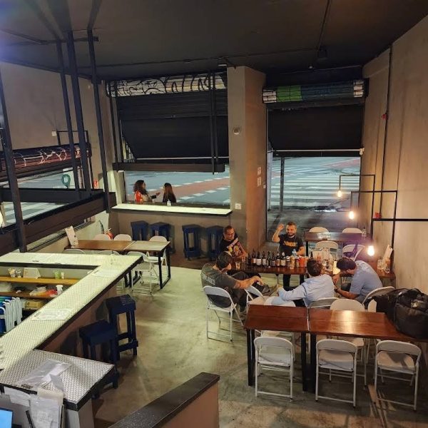 Cervejaria com torneiras de chopp e cervejas artesanais diferenciadas que representam diferentes culturas, lanches e pratos rústicos.